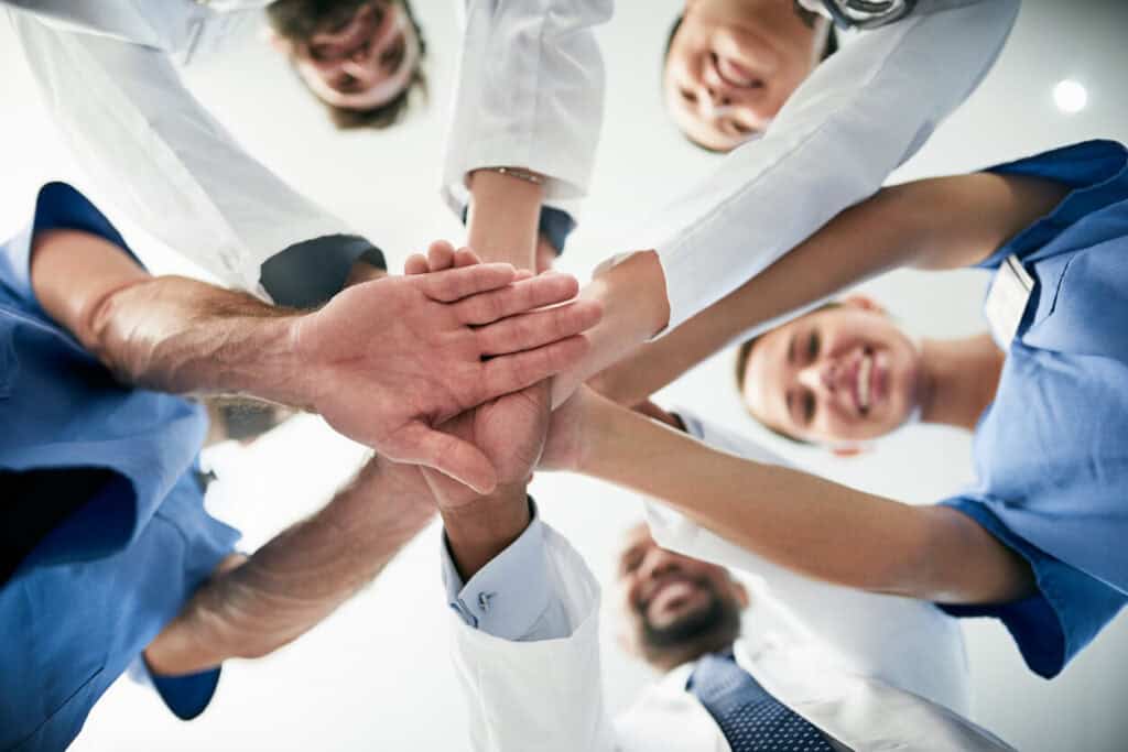 Ärzteteam der Augenklinik Dr. Hoffmann legt die Hände als Zeichen des Zusammenhalts übereinander